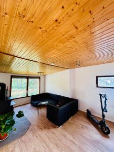 a living room with a black couch and wooden ceilings at Nature Bungalow in Ferch in Schwielowsee