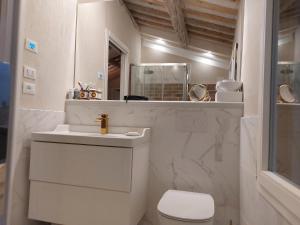 a white bathroom with a toilet and a sink at Fairytale old stonehouse in Brendola