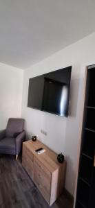 a living room with a chair and a tv on the wall at Smart Wellness Hotel TREZOR in Pécs