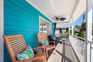 two chairs on a porch with a blue wall at Beach You To It in Anna Maria