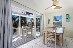 a dining room with a table and a balcony at Beach You To It in Anna Maria