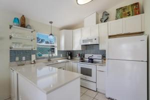 a kitchen with white cabinets and a white refrigerator at Beach You To It in Anna Maria