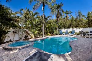 a swimming pool with chairs and palm trees at Beach You To It in Anna Maria +34 photos