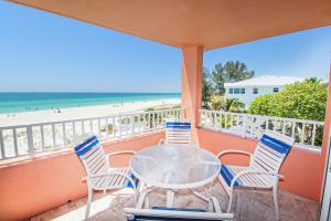 a table and chairs on a balcony with the beach at Beachfront Waves in Bradenton Beach