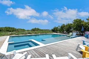 a swimming pool with chairs and a deck at Beachfront Bungalow in Holmes Beach