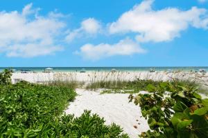 a sandy beach with people in the water and the ocean at Beachfront Bungalow in Holmes Beach