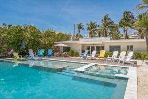 a swimming pool with chairs and a house at Beachfront Bungalow in Holmes Beach +50 photos