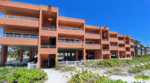 an orange apartment building on a beach with a blue sky at Beachfront Waves in Bradenton Beach
