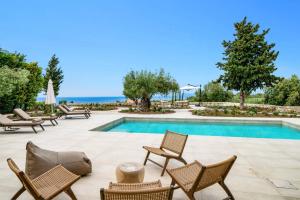 a patio with chairs and a swimming pool with the ocean in the background at Villa Cypressa by Villa Plus in Kalamitsi