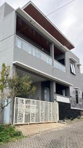 a house with a white fence in front of it at Villa Adela Sky Land Malang in Karangploso