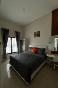 a bedroom with a large bed with an orange pillow at Villa Adela Sky Land Malang in Karangploso