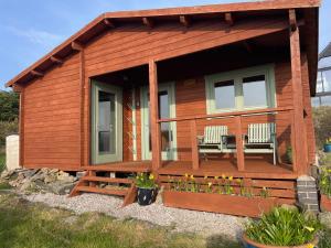 a wooden cabin with two chairs on the porch at Cosy Shepherd Huts and Cabin near Newborough, Anglesey in Gaerwen