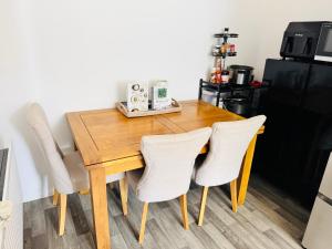 a dining room table with chairs and a black refrigerator at Ansari Palace in Worting