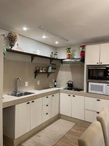 a kitchen with white cabinets and a sink and a microwave at Rancho Dreamland in Gaspar