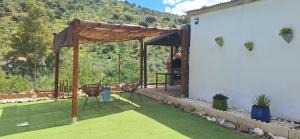 a patio with a table and chairs on the grass at La casa del rio cauche in Almogía