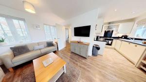 a living room with a couch and a kitchen at Life of Filey - Part of the The Bay Filey Holiday Village with pool, gym and direct beach access, pub, restaurant, tennis and meadows walks in Reighton