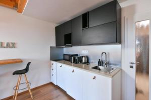 a kitchen with white cabinets and a sink and a stool at Relax in Korzo Lipno in Lipno nad Vltavou
