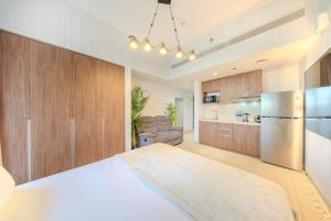 a kitchen and living room with a bed and a refrigerator at Luxury Studio With Private Garden - Uptown Al Zahia Sharjah in Ḩiz̧āyib az Zānah