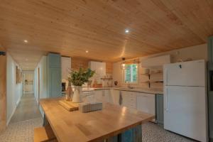 a kitchen with white appliances and a wooden ceiling at Riverfront Getaway with Hot Tub and Scenic Views in Mont-Tremblant +31 photos