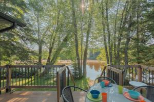 a table on a deck with a view of a lake at Riverfront Getaway with Hot Tub and Scenic Views in Mont-Tremblant