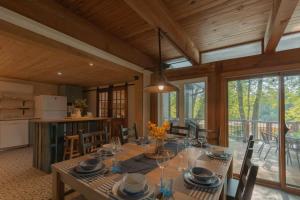 a dining room with a table and a kitchen with windows at Riverfront Getaway with Hot Tub and Scenic Views in Mont-Tremblant