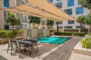 a patio with a table and chairs next to a swimming pool at Luxury Studio With Private Garden - Uptown Al Zahia Sharjah in Ḩiz̧āyib az Zānah