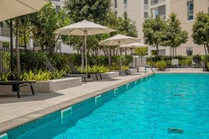 a swimming pool with chairs and umbrellas next to a building at Luxury Studio With Private Garden - Uptown Al Zahia Sharjah in Ḩiz̧āyib az Zānah