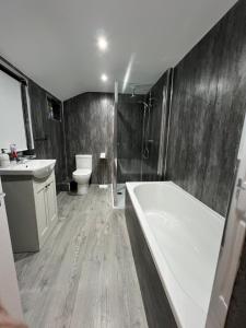 a bathroom with a tub and a toilet and a sink at Central Kettering Apartment by SJP Ideal for up to 3 Guests in Kettering +34 photos