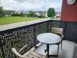 a table and chairs on a balcony with a horse pasture at DOMITYS - Les Arilles in Ifs