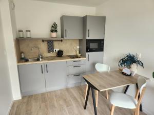 a kitchen with white cabinets and a wooden table at DOMITYS - Les Arilles in Ifs