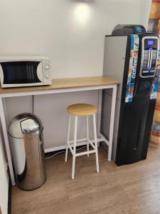 a desk with a microwave and a stool next to a refrigerator at Hotel des Voyageurs in Millau
