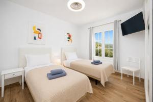 two beds in a white room with a window at Villa Yaiza Secret 1 in Yaiza +20 photos
