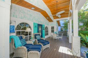 a covered porch with wicker chairs and a wooden ceiling at Buttonwood Cottage in Anna Maria