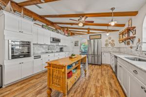 a kitchen with white cabinets and a wooden island at Buttonwood Cottage in Anna Maria