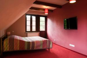 カジミエシュ・ドルニにあるCztery Pokojeの赤い壁にテレビとベッドが備わるベッドルーム1室が備わります。