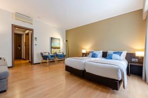 a bedroom with a large bed with blue pillows at TURIM Aveiro Palace Hotel in Aveiro