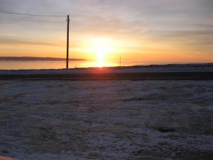 una puesta de sol sobre el océano con un poste en primer plano en Motel Leblanc, en Carleton-sur-Mer