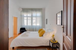 a bedroom with a bed with white sheets and yellow pillows at Chromatica - di fronte a Galleria Bomb in Gorizia +24 photos