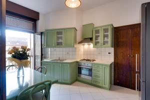 a kitchen with green cabinets and a glass table at Chromatica - di fronte a Galleria Bomb in Gorizia