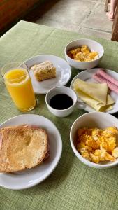 a table with plates of breakfast food and orange juice at Pousada Alto Pirapitinga in Resende