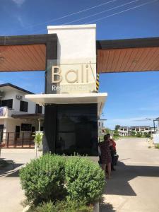 two people standing in front of a building with a sign at Bali-Inspired Pool Haus Cebu in Lapu Lapu City