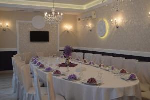 a banquet room with a long table with white chairs at Hotel Bulevard Prestige in Slatina