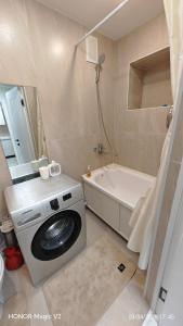 a bathroom with a washing machine and a bath tub at Aktau 4-31 in Aktau