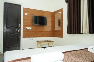 a room with two beds and a tv on the wall at Hotel laxminarayan niwas in Shirdi