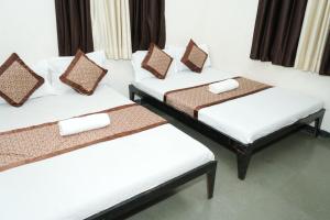 a group of three beds in a room at Hotel laxminarayan niwas in Shirdi