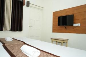 a hotel room with a bed with a tv on the wall at Hotel laxminarayan niwas in Shirdi