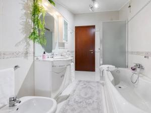 a white bathroom with a tub and a sink and a bath tub at Casa di Iaio - Wi-Fi Netflix Home Cinema in Gorizia