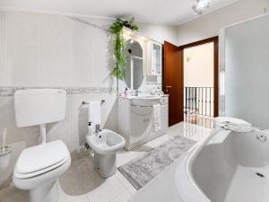 a white bathroom with a toilet and a sink and a tub at Casa di Iaio - Wi-Fi Netflix Home Cinema in Gorizia +3 photos
