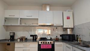 a kitchen with white cabinets and a stove top oven at Viento Sur Anfitrionas "Centro" in Puerto Madryn +13 photos