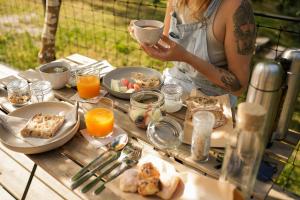 a woman holding a cup of coffee on a table with food at Amaraxe Ecoglamping in Miñortos